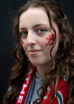 Young female Wales rugby fan painted face and scarf
