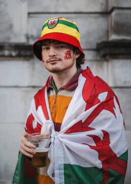 Young Wales rugby fan with flag around shoulders and bucket hat